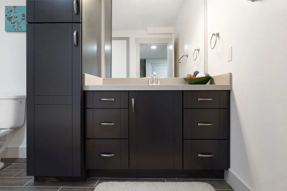 gorgeous bathroom with dark cabinetry amidst white surroundings