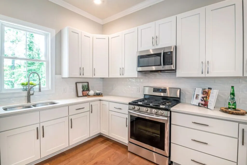 white wooden kitchen cabinets and black microwave oven